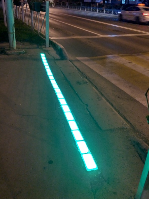 Границы пешеходных переходов обозначены полосами, набранными из прозрачной тротуарной плитки, которая подсвечивается изнутри, синхронно со светофором.